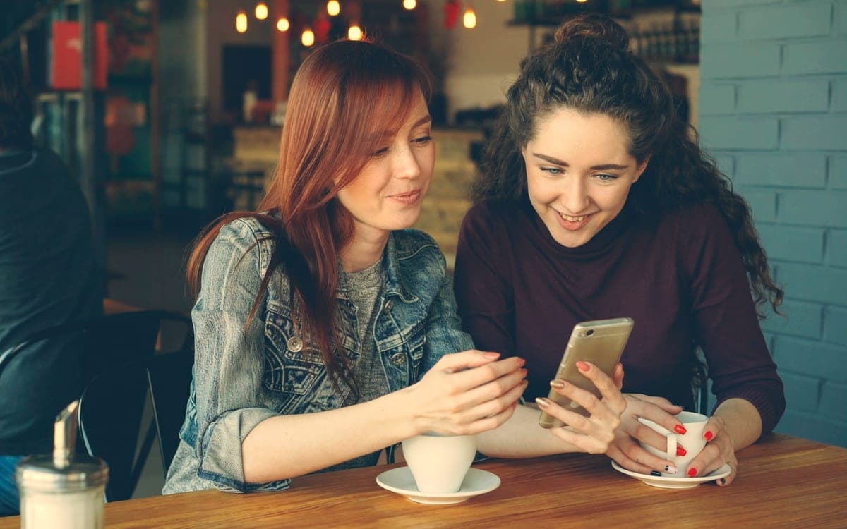 Deux amies choisissent ensemble les commerçants sur un téléphone